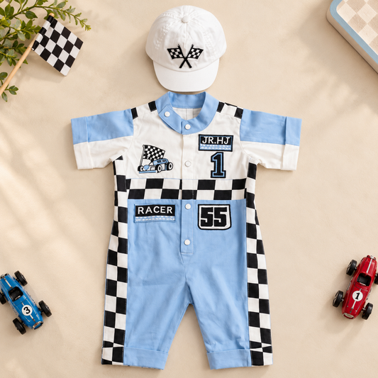 A baby short-sleeve romper and matching cap laid flat on a beige surface. The romper is light blue and white with black-and-white checkered side panels and racing graphics, including the number 55 and patches reading JR.