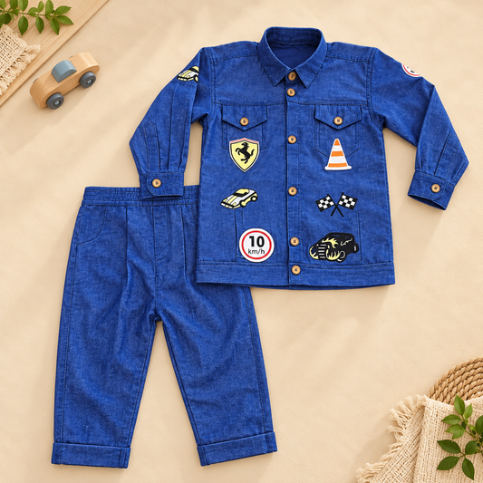 A toddler boy's two-piece denim outfit set consisting of a long-sleeve button-up shirt and matching pants, laid flat on a beige background with decorative props like a toy car and plants.