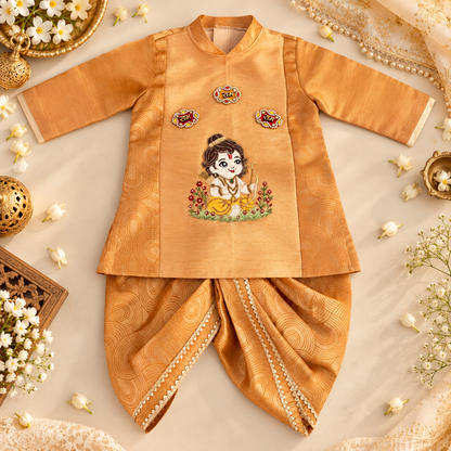 A traditional Indian baby outfit set in golden yellow fabric, featuring a long-sleeve embroidered top and matching pants, styled in a flat lay with decorative flowers and jewelry.