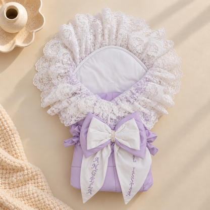A lavender and white baby bonnet with a lace headband, white bow, and embroidered name 'Angela' on a beige background.