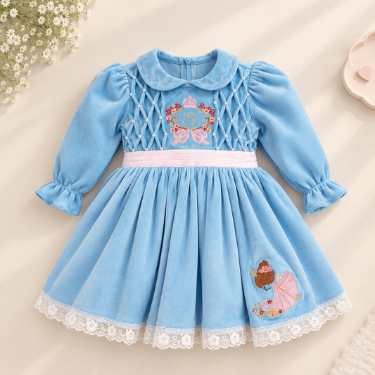 A baby girl's light blue velvet dress with long puff sleeves, a Peter Pan collar, and embroidered details. The bodice features an embroidered carriage with a crown and the letter 'B', a white waistband, and a lace-trimmed hem.