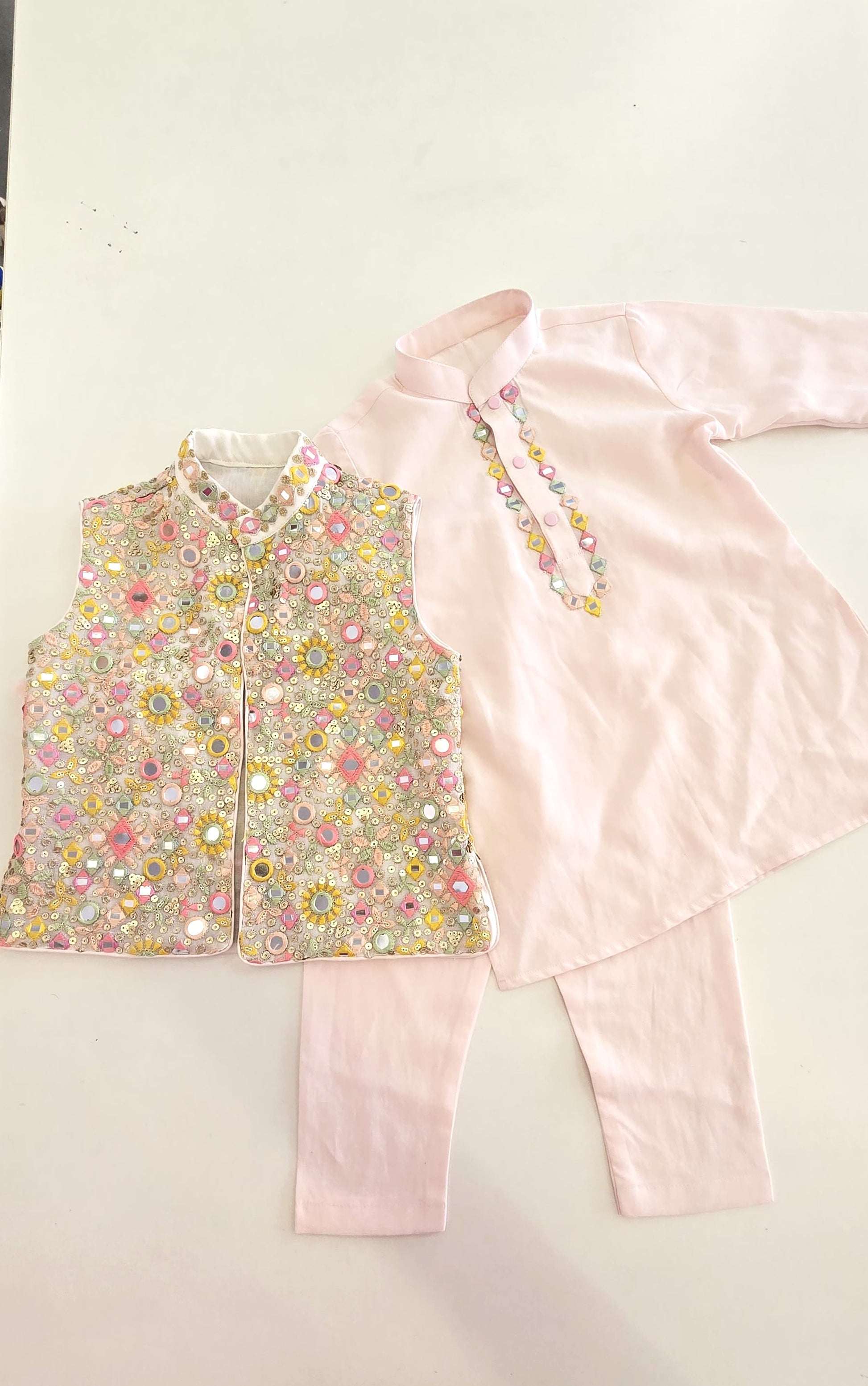 Traditional outfit with floral top, pink pants, and dupatta on a white background