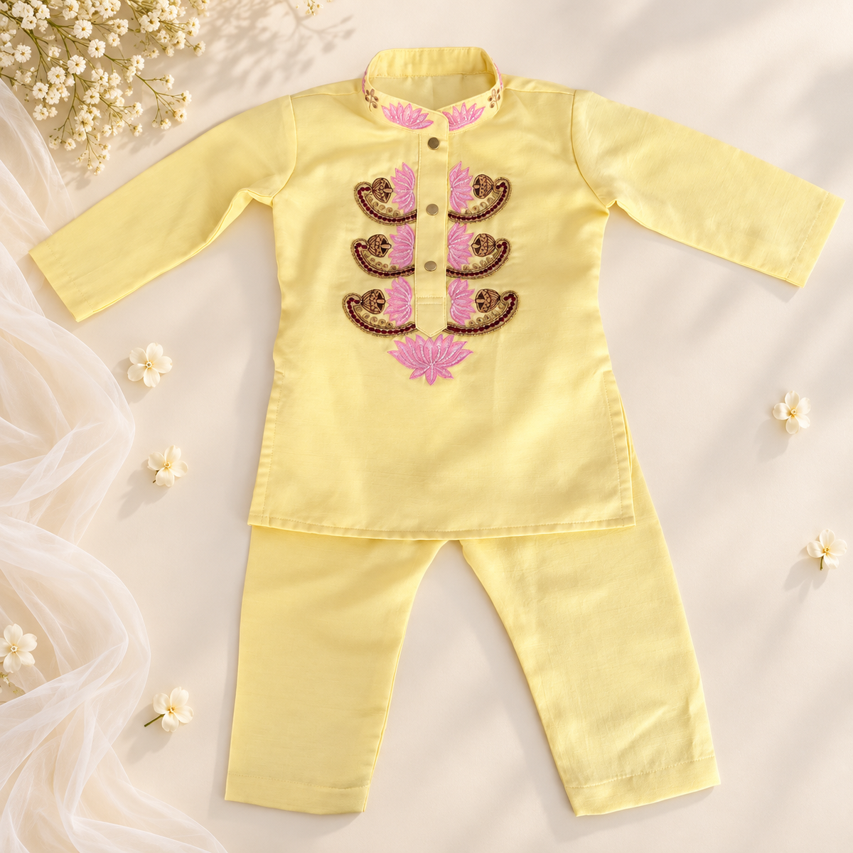 A baby's two-piece traditional outfit consisting of a long-sleeve top and matching pants in pale yellow. The top features a mandarin collar, buttoned front, and a decorative chest panel with pink and brown embroidered paisley patterns.